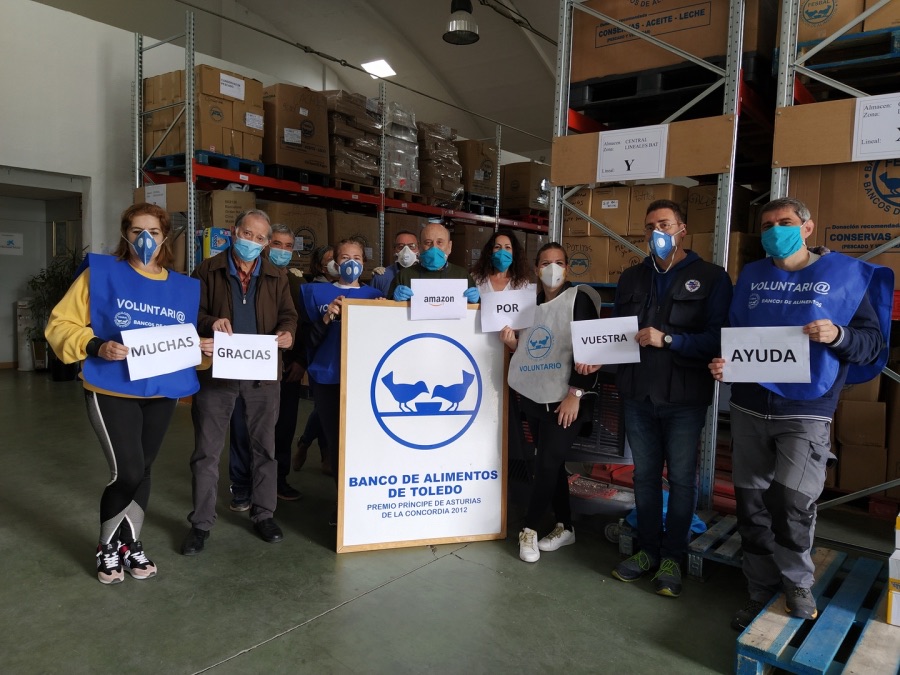 Voluntarios con mascarilla en el almacén sujetan carteles de agradecimiento a Amazon