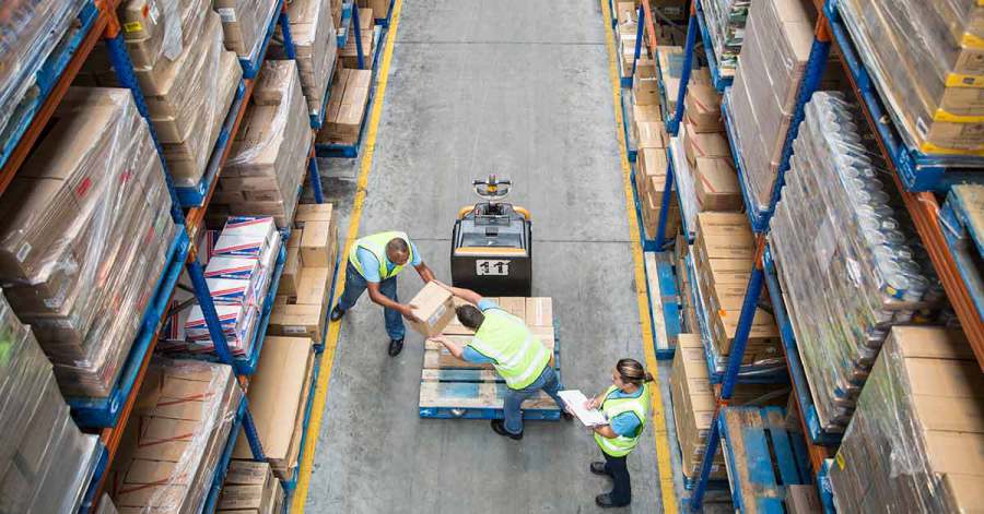 Operarios moviendo cajas con una transpaleta entre las estanterías de un almacén