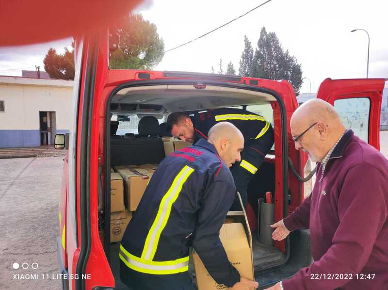 Un bombero y un voluntario descargan cajas de alimentos de una furgoneta de bomberos