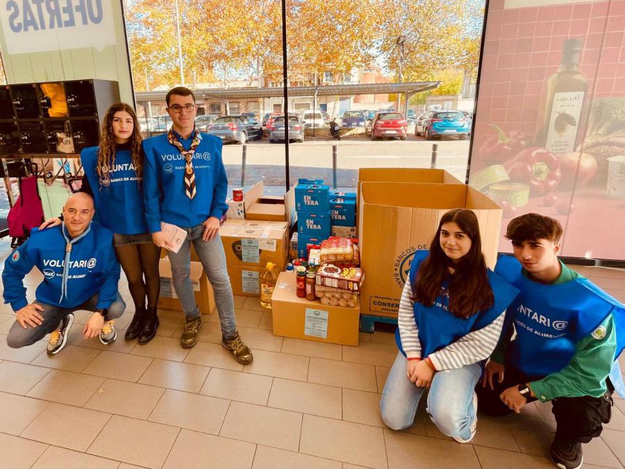 Voluntarios junto a las cajas de alimentos recogidos en la entrada de un supermercado