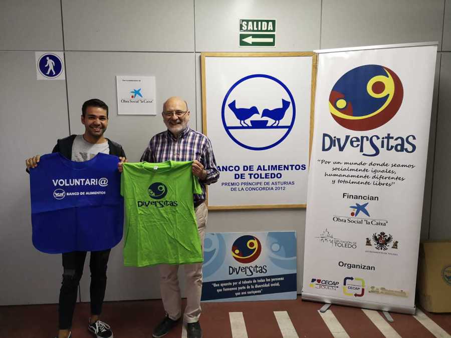 Un voluntario del Banco de Alimentos y un representante de Diversitas muestran sus camisetas junto a los carteles del festival