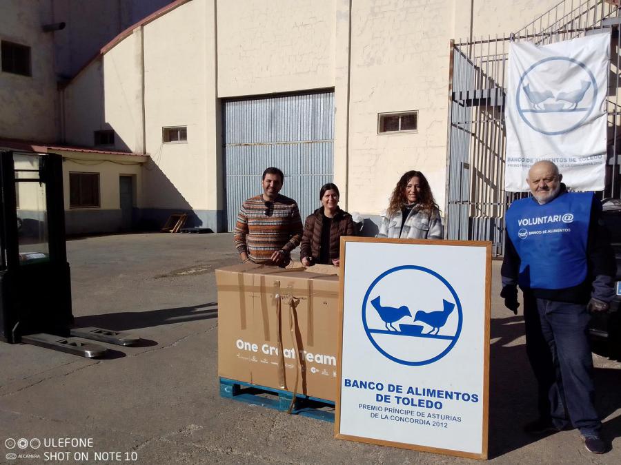 Representantes del CEIP Ramón y Cajal de Lominchar y voluntarios junto a las cajas donadas, a la entrada del almacén