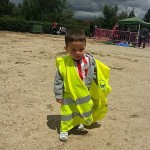 Niño pequeño con chaleco amarillo de voluntario en una actividad al aire libre