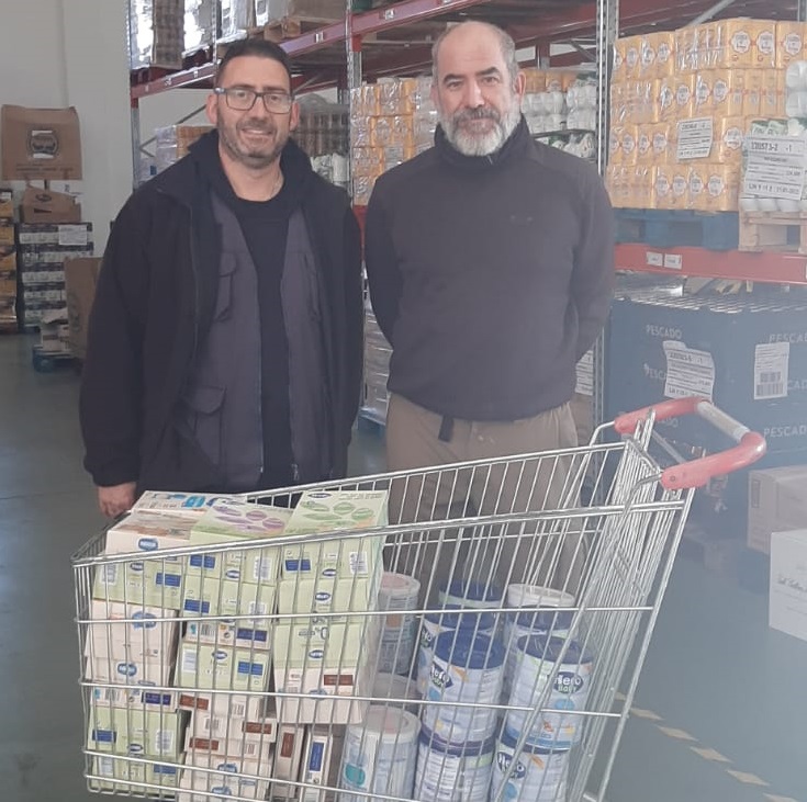 Representantes de Global Arqueología junto a un carro con alimentación infantil