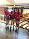 Tres chicas con patines y camisetas de la campaña Pulsera Solidaria en un centro comercial