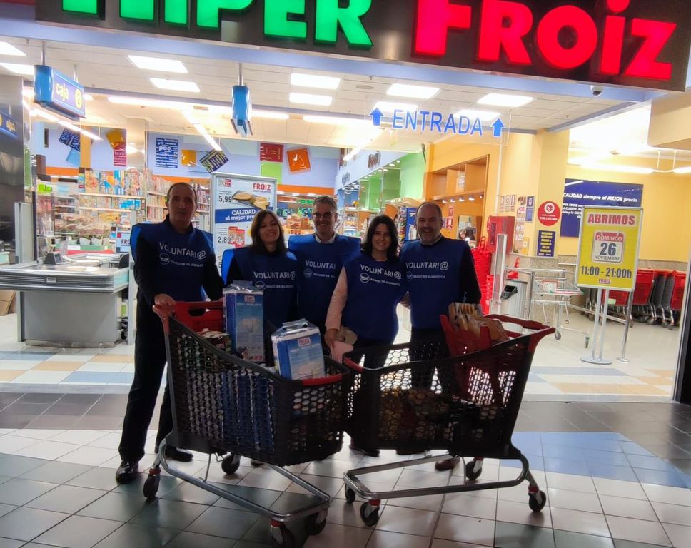 Voluntarios con carros de alimentos a la entrada de un supermercado Froiz
