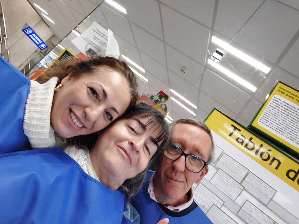 Selfi de tres voluntarios en la zona de cajas de un supermercado
