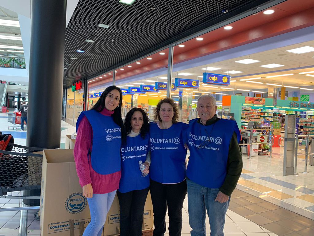 Cuatro voluntarios con petos a la entrada de un supermercado