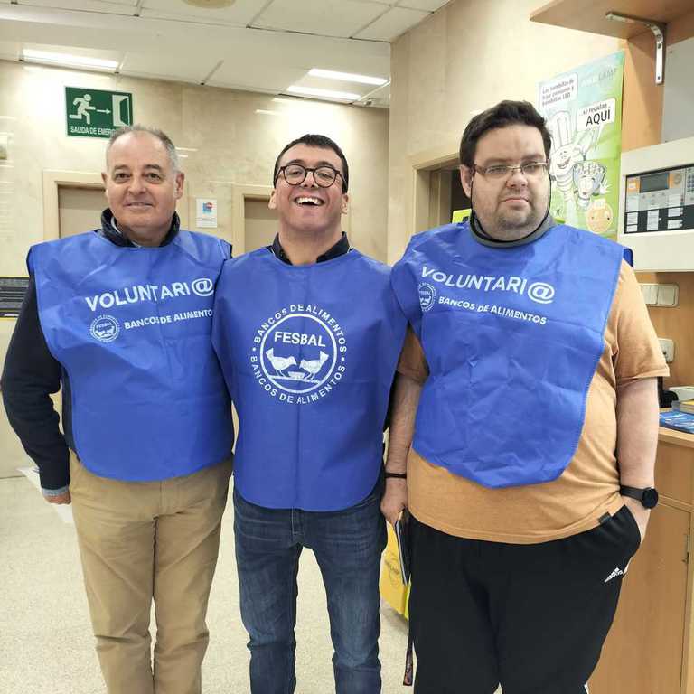 Tres voluntarios sonrientes con petos azules