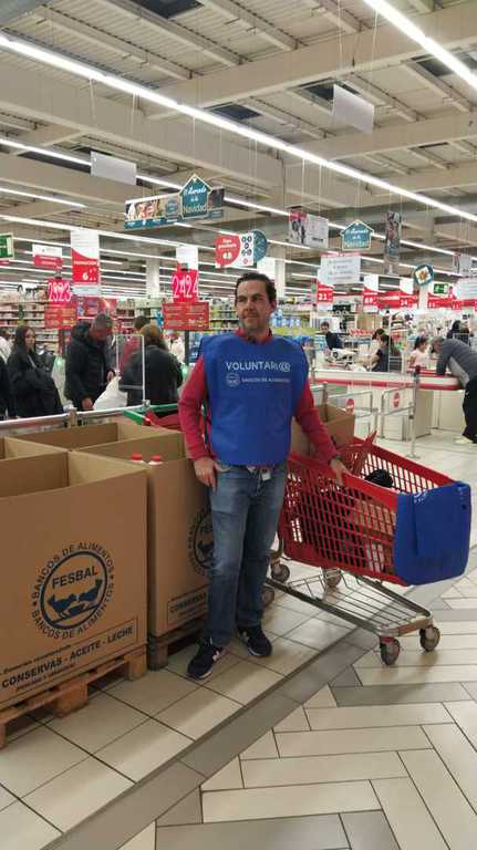 Voluntario junto a un carro y las cajas de recogida en un hipermercado