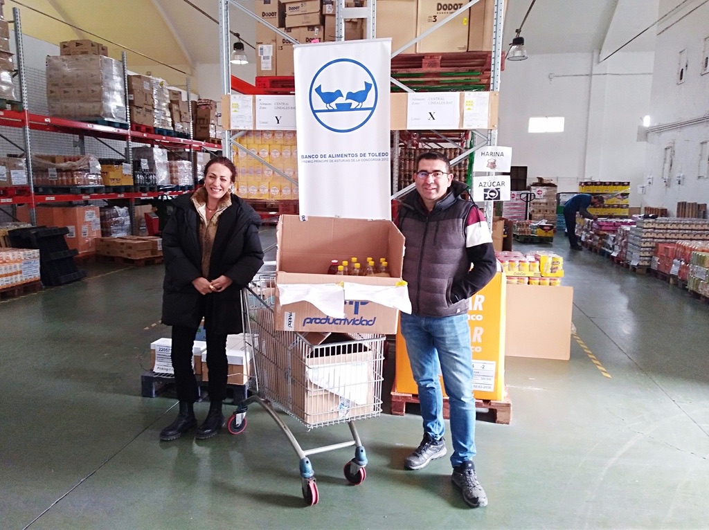 Dos personas con un carro de alimentos donados en el almacén del Banco de Alimentos