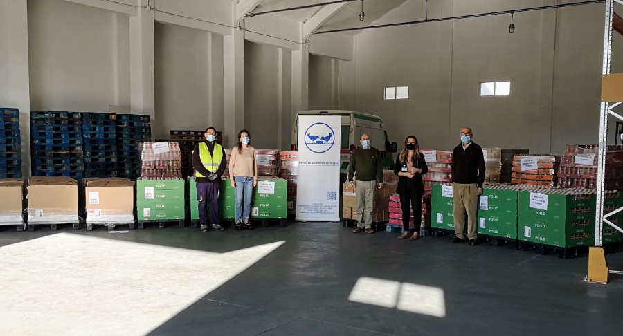 Palés de alimentos donados por Mercadona en el almacén, con representantes de ambas entidades