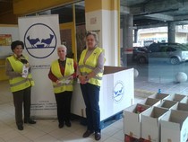 Voluntarias del Banco de Alimentos con chaleco amarillo junto al punto de recogida en un supermercado Simply
