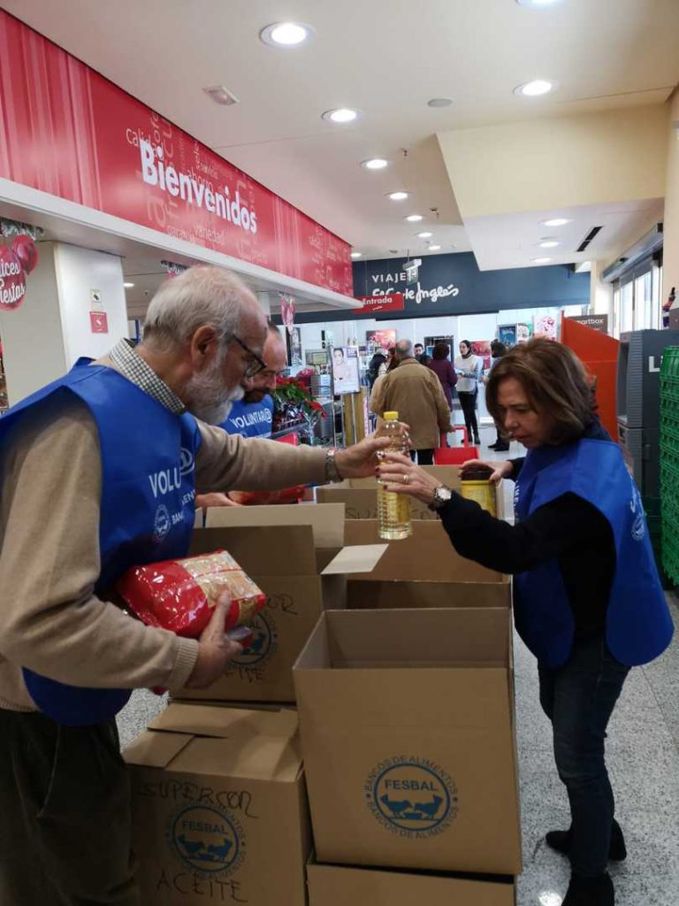 Dos voluntarios recogen alimentos en cajas a la entrada de un supermercado