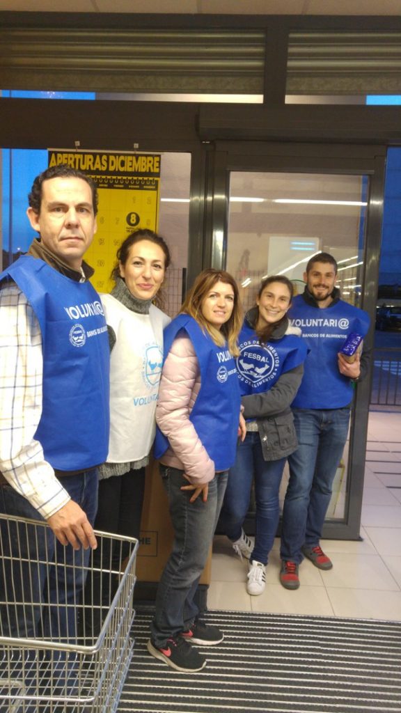 Grupo de voluntarios con petos azules en la entrada de un supermercado