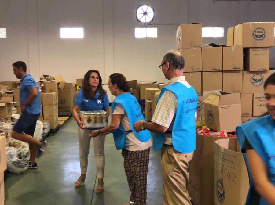 Voluntarios de La Caixa trabajando entre cajas en el almacén del Banco de Alimentos